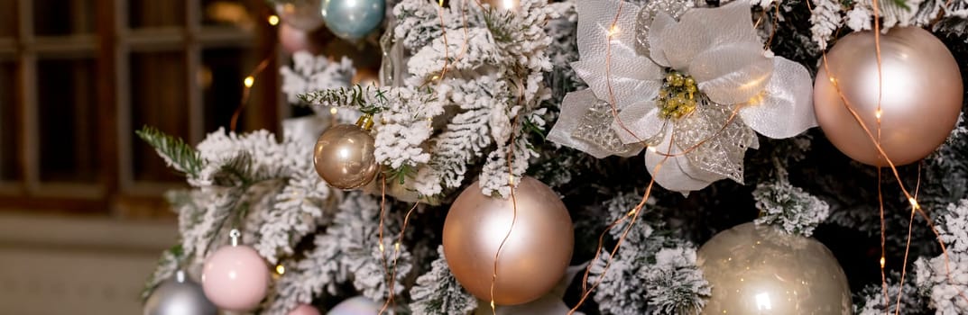 Artificial Christmas tree in a bright interior with silver flowers and snow on the branches. The concept of New year and Christmas