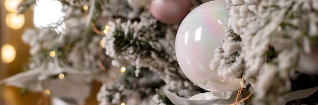 Artificial Christmas tree in a bright interior with silver flowers and snow on the branches. The concept of New year and Christmas