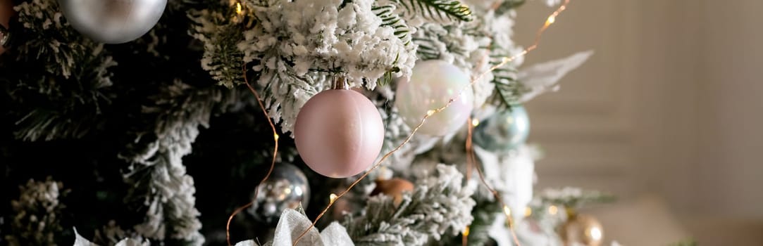 Artificial Christmas tree in a bright interior with silver flowers and snow on the branches. The concept of New year and Christmas