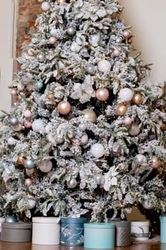 Artificial Christmas tree in a bright interior with silver flowers and snow on the branches. The concept of New year and Christmas