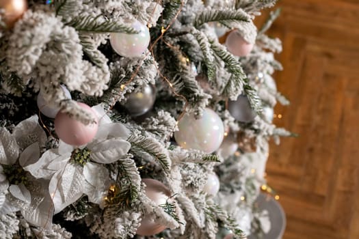Artificial Christmas tree in a bright interior with silver flowers and snow on the branches. The concept of New year and Christmas