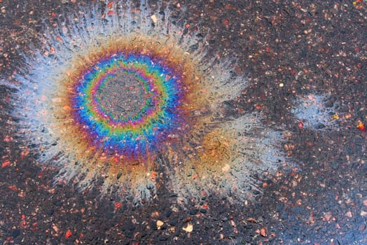 A fuel or oil stain on wet asphalt on a rainy day.