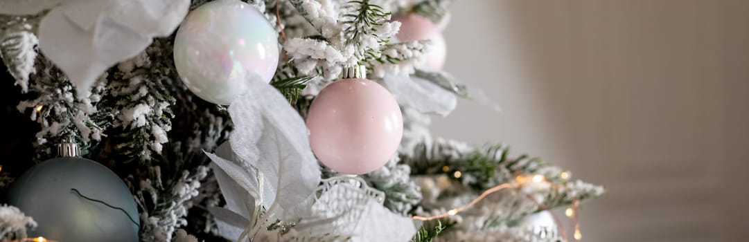 Christmas holiday composition. Christmas tree fir branches, silver balls on top border on pink pastel background with copy space.