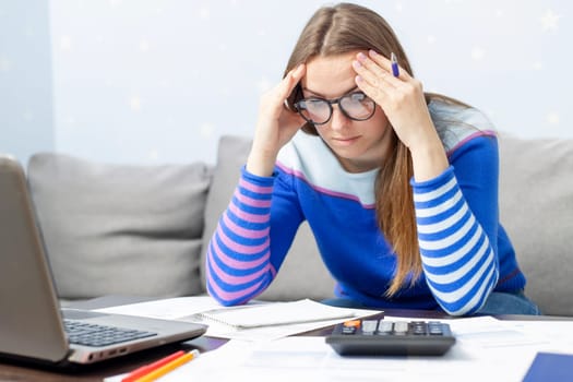 Woman using calculator for calculate domestic bills at home, doing paperwork for paying taxes