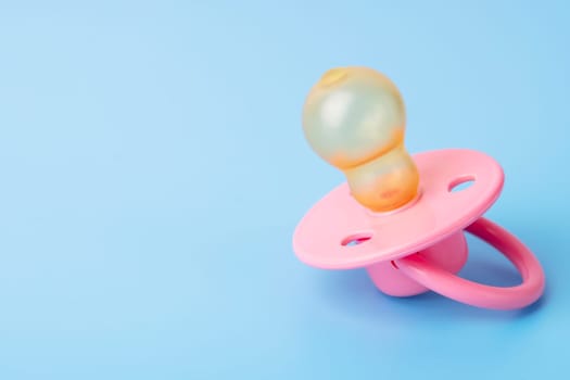 Orthodontic pacifier on a blue background. Pink baby pacifier on a blue background, space for text.