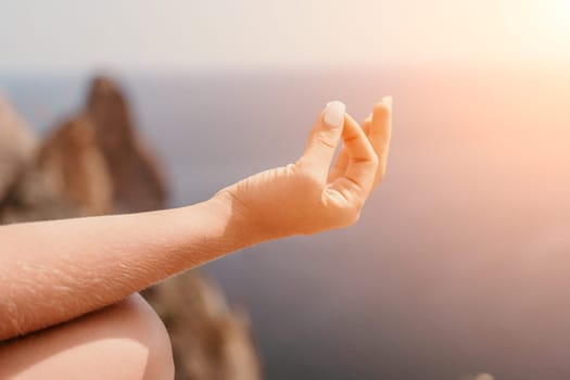 Middle aged well looking woman with black hair doing Pilates with the ring on the yoga mat near the sea on the pebble beach. Female fitness yoga concept. Healthy lifestyle, harmony and meditation.