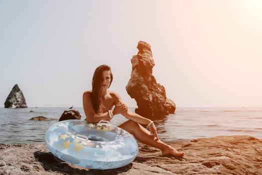 Woman summer sea. Happy woman swimming with inflatable donut on the beach in summer sunny day, surrounded by volcanic mountains. Summer vacation concept