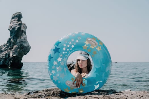 Woman summer sea. Happy woman swimming with inflatable donut on the beach in summer sunny day, surrounded by volcanic mountains. Summer vacation concept