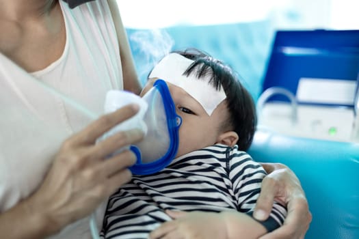 Little boy having inhalation for easing cough. Mother Helping Little Son Using Nebulizer During Inhalation.