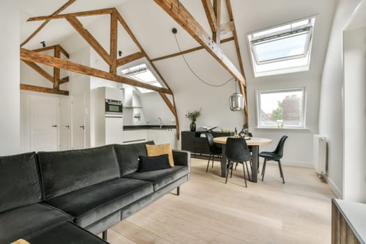 a living room with wood beams on the ceiling and black leather couch in the room is well lit by sunlight