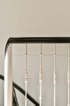 a black and white staircase with wooden balknots on the handrail, which is part of a set of stairs