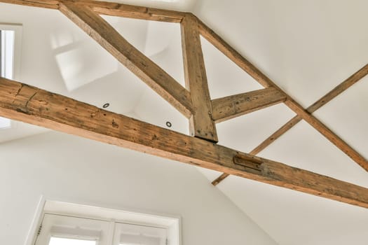 some wood beams on the ceiling in a room with white walls and an open window to the light is shining through