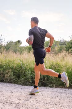 vertical photo of an unrecognizable man running in the countryside, concept of sport in nature and active lifestyle