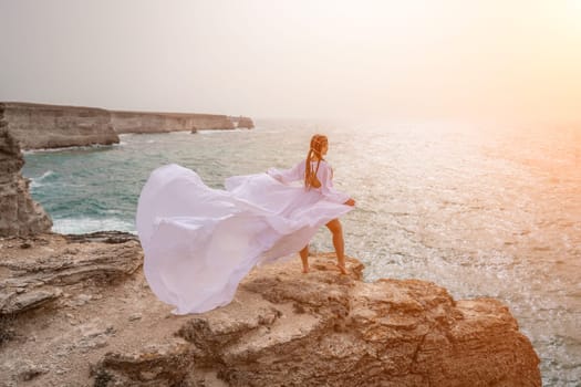 Woman sea white dress. Happy freedom woman on the beach enjoying and posing in white dress. Rear view of a girl in a fluttering white dress in the wind. Holidays, holidays at sea