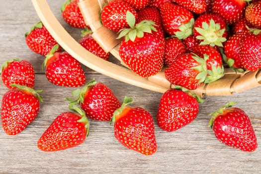 Ripe strawberry in wicker basket on a wooden background