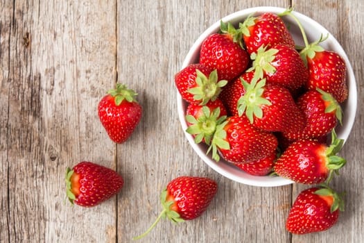 Red strawberry in a bowl on wooden background