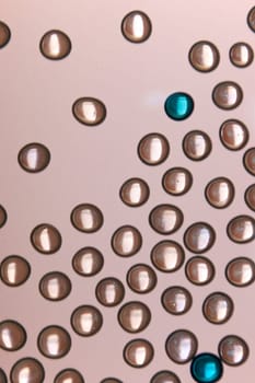 Light is shining through round glass beads on a frosted glass surface, seen from below making interesting abstract background.