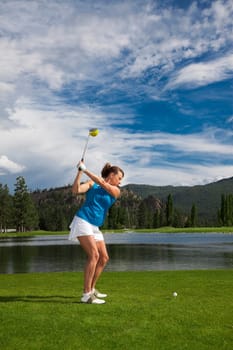 Outdoor photo of attractive woman golfing.
