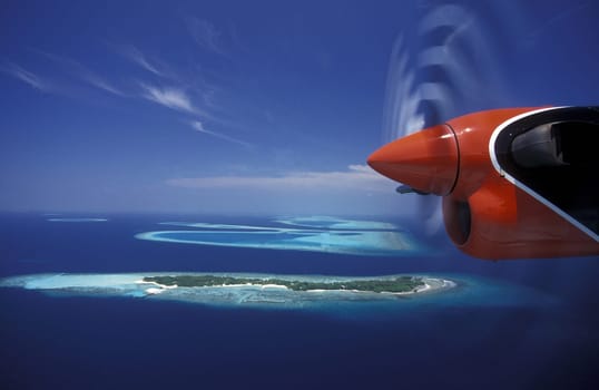A seaplane in the air over the islands of the Maldives in the Indian Ocean.