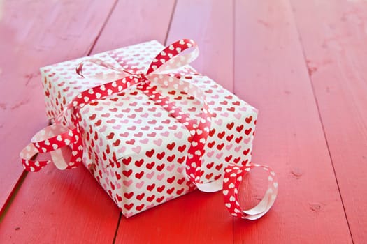 Small gift with hearts and bow on red
