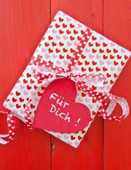 Small gift with hearts and bow on red