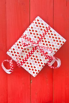 Small gift with hearts and bow on red