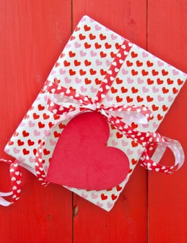 Small gift with hearts and bow on red