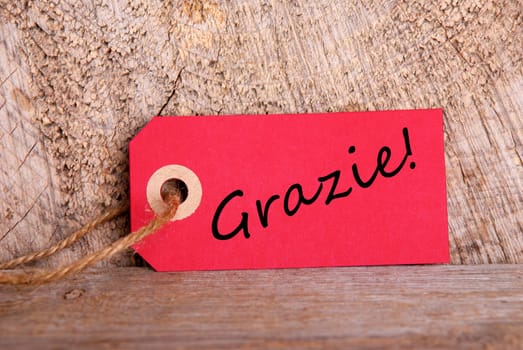 A Red Tag on Wood with the Italian Word Grazie which means Thanks