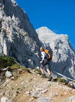Young woman on a sunny day hiking in high mountains