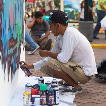 LIMA,PERU - MARCH 3,2012: Unidentified young man spraying a wall on the Latir Latino,the first Latin-American Street Art Festival on March 3,2012 in Miraflores,Lima,Peru. Many national and international street artists participated on this Festival,which was organised by the Municipality of Miraflores.