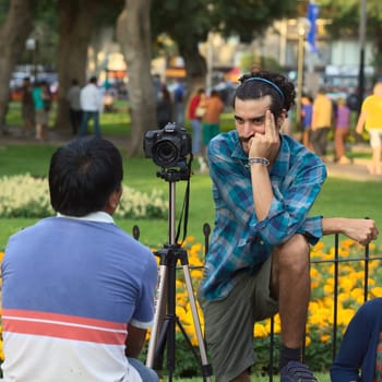 LIMA,PERU - MARCH 3,2012: Unidentified young man taking a photograph of another person with a Canon EOS 60D camera in Parque Kennedy on March 3,2012 in Miraflores,Lima,Peru