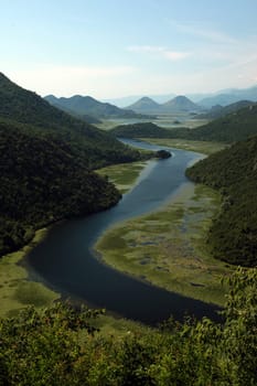 The landscape at Rijeka Crnojevica with the river Rijeka Crnojevica at the western end of the Skadarsko Jezero lake or Skadar lake in Central Montenegro in Montenegro in the Balkans on the Mediterranean Sea in Europe.