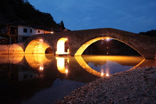 The landscape with the stone bridge of Rijeka Crnojevica with the river Rijeka Crnojevica at the western end of the Skadarsko Jezero lake or Skadar lake in Central Montenegro in Montenegro in the Balkans on the Mediterranean Sea in Europe.