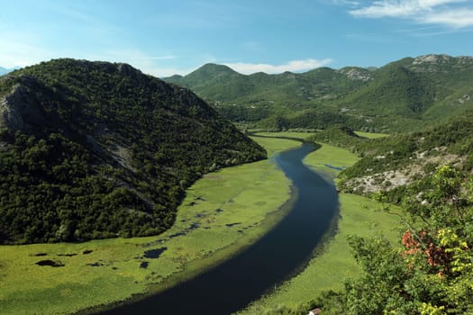 The landscape at Rijeka Crnojevica with the river Rijeka Crnojevica at the western end of the Skadarsko Jezero lake or Skadar lake in Central Montenegro in Montenegro in the Balkans on the Mediterranean Sea in Europe.