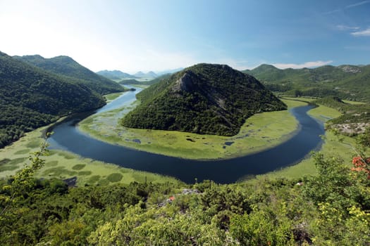 The landscape at Rijeka Crnojevica with the river Rijeka Crnojevica at the western end of the Skadarsko Jezero lake or Skadar lake in Central Montenegro in Montenegro in the Balkans on the Mediterranean Sea in Europe.