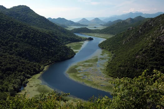 The landscape at Rijeka Crnojevica with the river Rijeka Crnojevica at the western end of the Skadarsko Jezero lake or Skadar lake in Central Montenegro in Montenegro in the Balkans on the Mediterranean Sea in Europe.