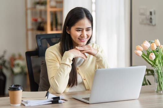 A dedicated freelance businesswoman interacts with clients on her laptop at home, embodying professionalism and commitment.