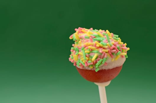 Cake pop with sugar pearls on a green background