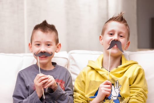 two kids making funny faces with fake moustaches