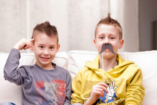 two kids making funny faces with fake moustaches