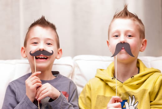 two kids making funny faces with fake moustaches