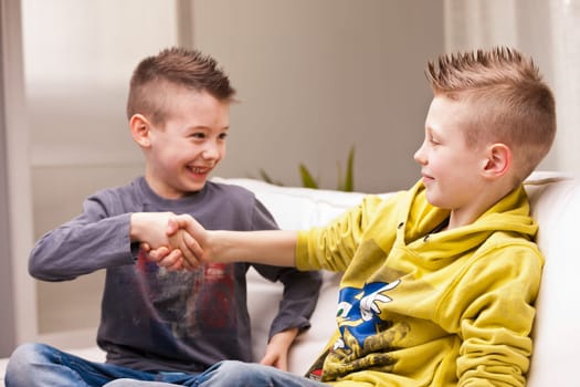 two little boys handshaking with a smile