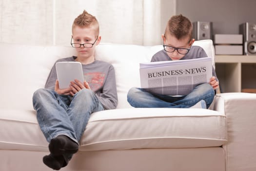two little boys reading on newspapers or digital devices