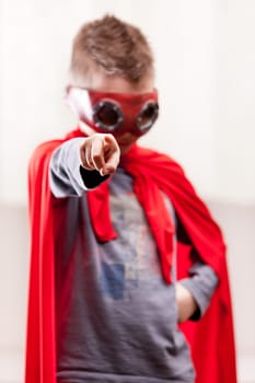 a little kid playing as a red cloak serious superhero