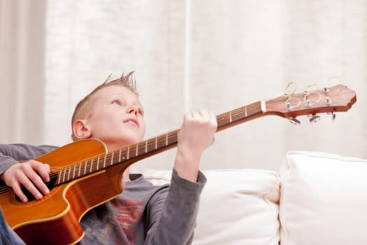little boy playing guitar on a sofa in his living room