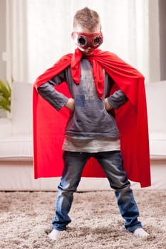 a little kid playing as a red cloak serious superhero