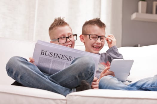 two little boys reading on newspapers or digital devices