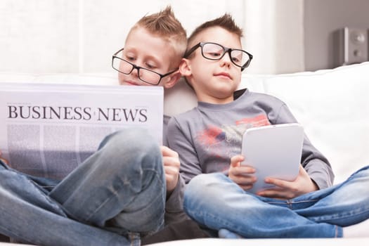 two little boys reading on newspapers or digital devices