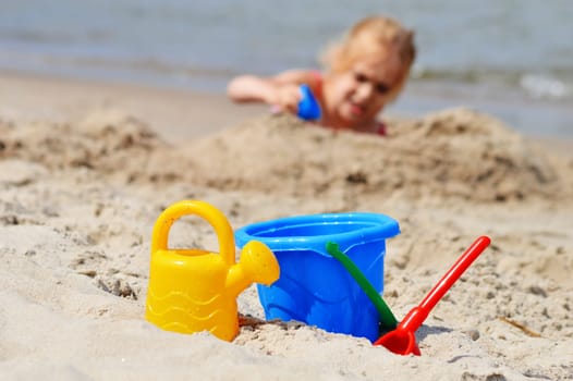 Little girl playing on the sand beach.