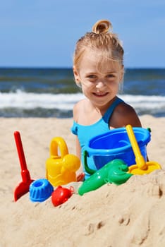 Little girl playing on the sand beach.